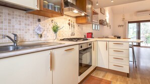 A modern kitchen with white cabinets, stainless steel appliances, and wooden countertops. - Le Conchiglie by Interhome (Olbia)