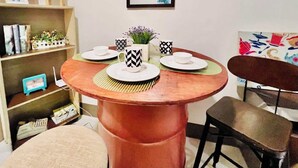 A dining area with a round wooden table, two chairs, and a bookshelf with various items. - Cozy Home in BGC (taguig)