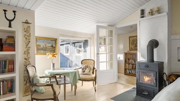 A cozy living room with a fireplace, wooden bookshelves, a dining table with chairs, and a view through an open door. - Beautiful home in ølsted with WiFi (Ølsted)