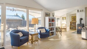 A spacious living room with a large sliding glass door leading to a patio, a fireplace, and a bookshelf filled with books. - Beautiful home in ølsted with WiFi (Ølsted)