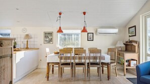A spacious kitchen with wooden cabinets, a dining table with chairs, pendant lights, and a large window with a view of trees. - Beautiful home in ølsted with WiFi (Ølsted)