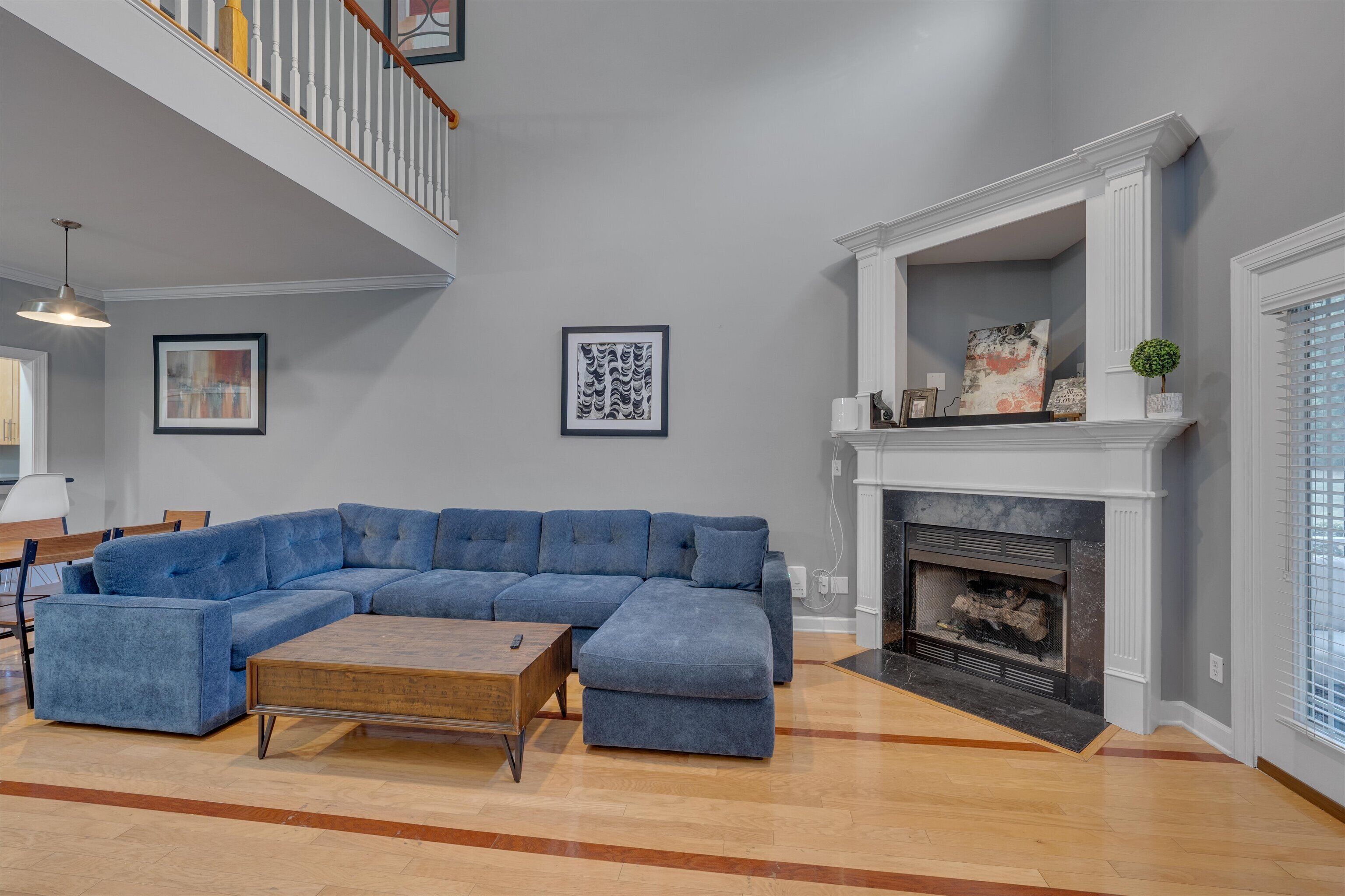 A spacious living room with a large sectional sofa, a wooden coffee table, and a fireplace.