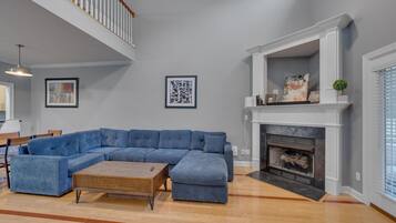 A spacious living room with a large sectional sofa, a wooden coffee table, and a fireplace.