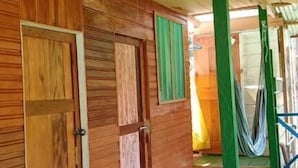 Un interior de madera con piso verde, un abanico y una hamaca.