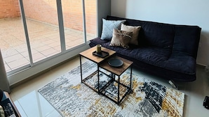 A modern living room with a dark blue sofa, a small wooden coffee table, and a patterned rug. - Smart apartment in exclusive area  (Popayán)