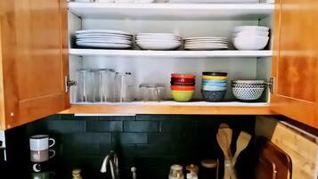 A kitchen with wooden cabinets, a sink, and various kitchen utensils.