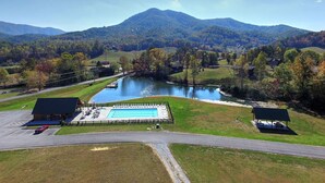 Une piscine dotée d’une plage, entourée d’un espace de stationnement et d’un abri pour pique-nique.