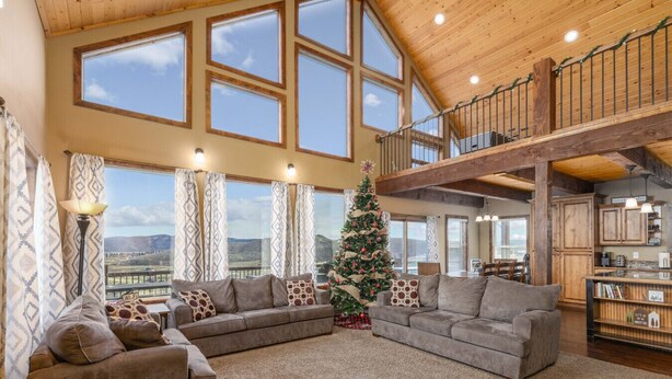 Un salón amplio con un gran ventanal, techo de madera y un árbol de Navidad.