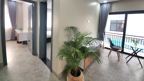 A modern hotel room with a balcony, a dining area, and a large potted plant. - My Natural Villas by You Long (Siem Reap)