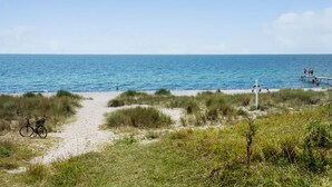 Ein Strandweg, der zum Meer führt, mit einem Fahrrad, das links abgestellt ist.