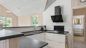 Eine moderne Küche mit einem schwarzen Herd, weißen Schränken und einem großen Fenster.