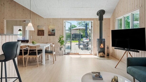 Ein modernes Wohnzimmer mit Fernseher, Kamin und Essbereich mit Holzmöbeln.