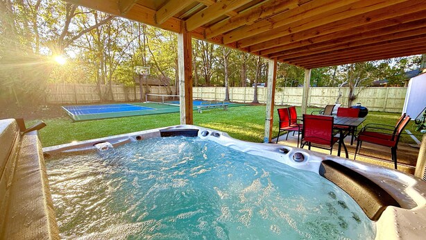 Un jacuzzi bajo una pérgola de madera con vistas a un jardín trasero.