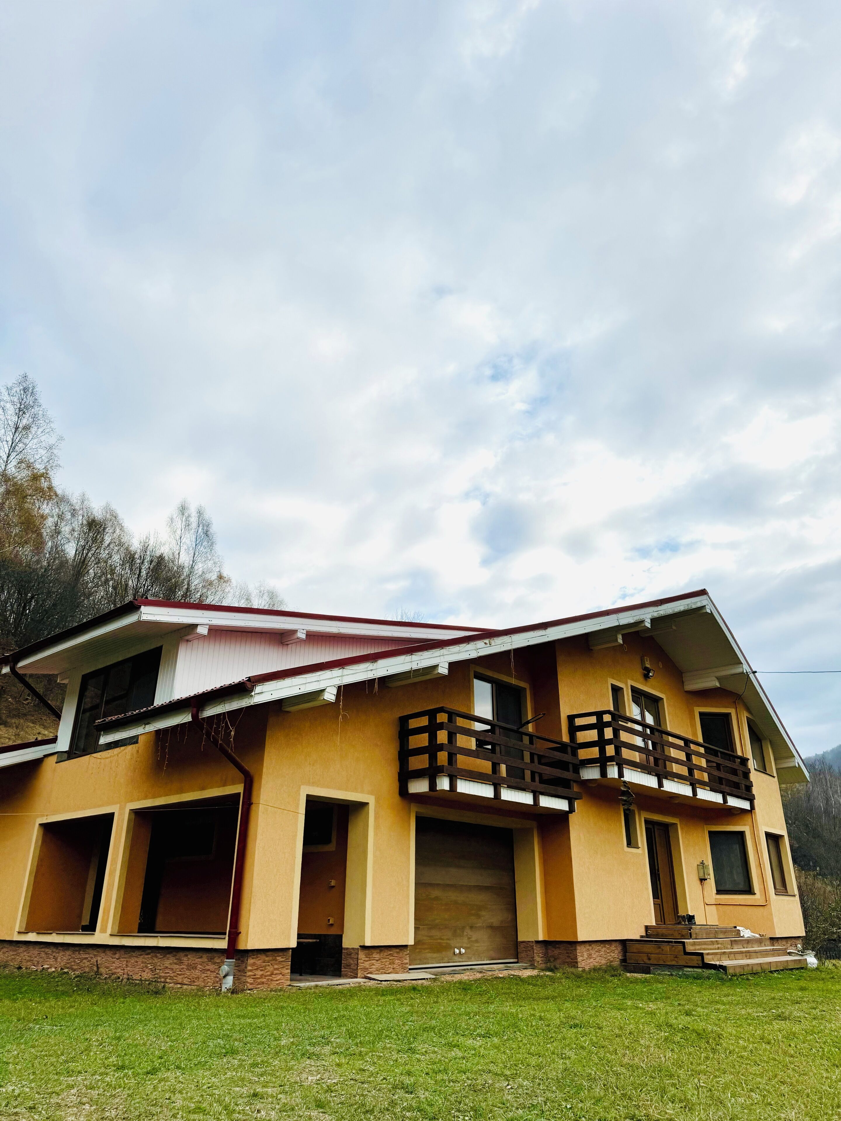 A two-story house with a balcony, a garage, and a front door.