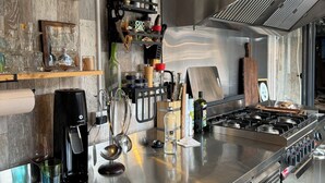 A modern kitchen with stainless steel appliances, wooden shelves, and a variety of kitchenware. - Rai Villa (Banita)