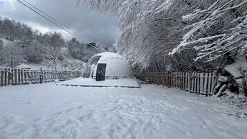 A snow-covered outdoor area with a gazebo, a snow-covered fence, and a snow-covered bench.