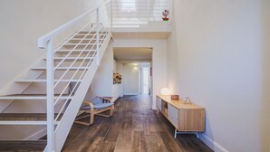 A modern interior with a wooden staircase, a bench, and a wooden console table.