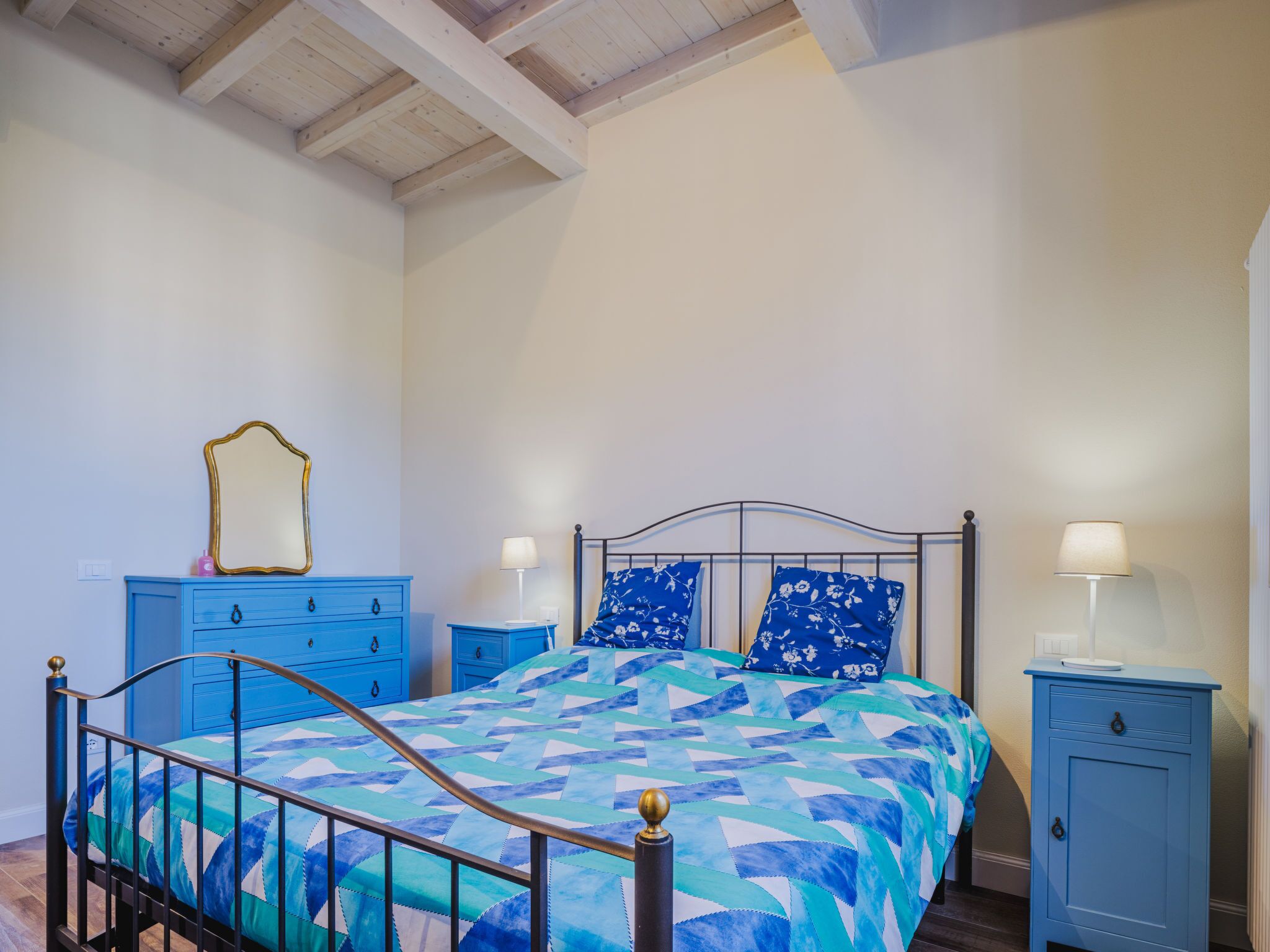 Una camera da letto con un letto, due comodini, una cassettiera e uno specchio.