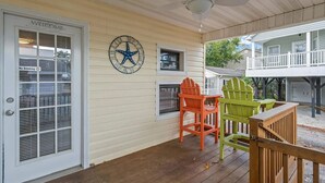 A covered porch with a "Welcome" sign, a clock, and Adirondack chairs. - 1309 Ocean Lakes Pet Friendly Golf Cart⛱️🏝️🩱🌊👙☀️🐚 (Myrtle Beach)