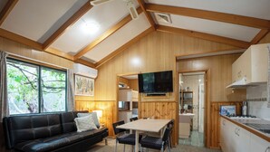 Een gezellig interieur van een blokhut met een zithoek, eethoek en keuken.