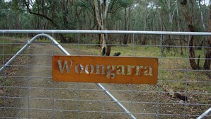 Een metalen hek met een bord waarop 'Woongarra' staat.