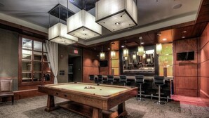 A pool table in a room with a bar area, wooden paneling, and a large mirror. - Baltimore executive Furnished rentals (Baltimore)