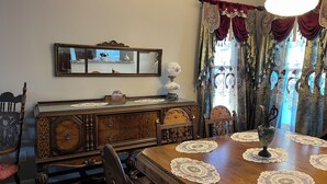 A dining room with a wooden table, chairs, a chandelier, a mirror, and ornate curtains. - Come enjoy the Victorian charm of this beautiful home. (La Junta)