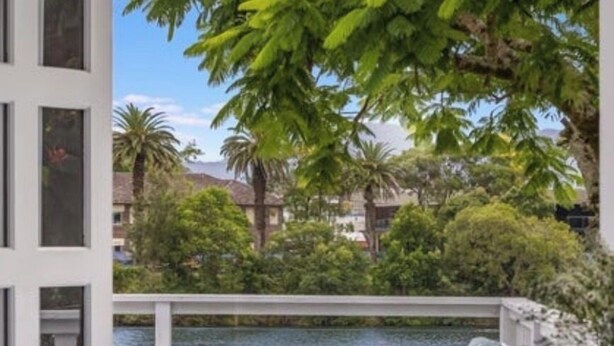 A covered outdoor area with a view of a lake, surrounded by greenery and buildings.