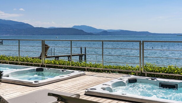 A pool area with hot tubs and a view of a lake and mountains.