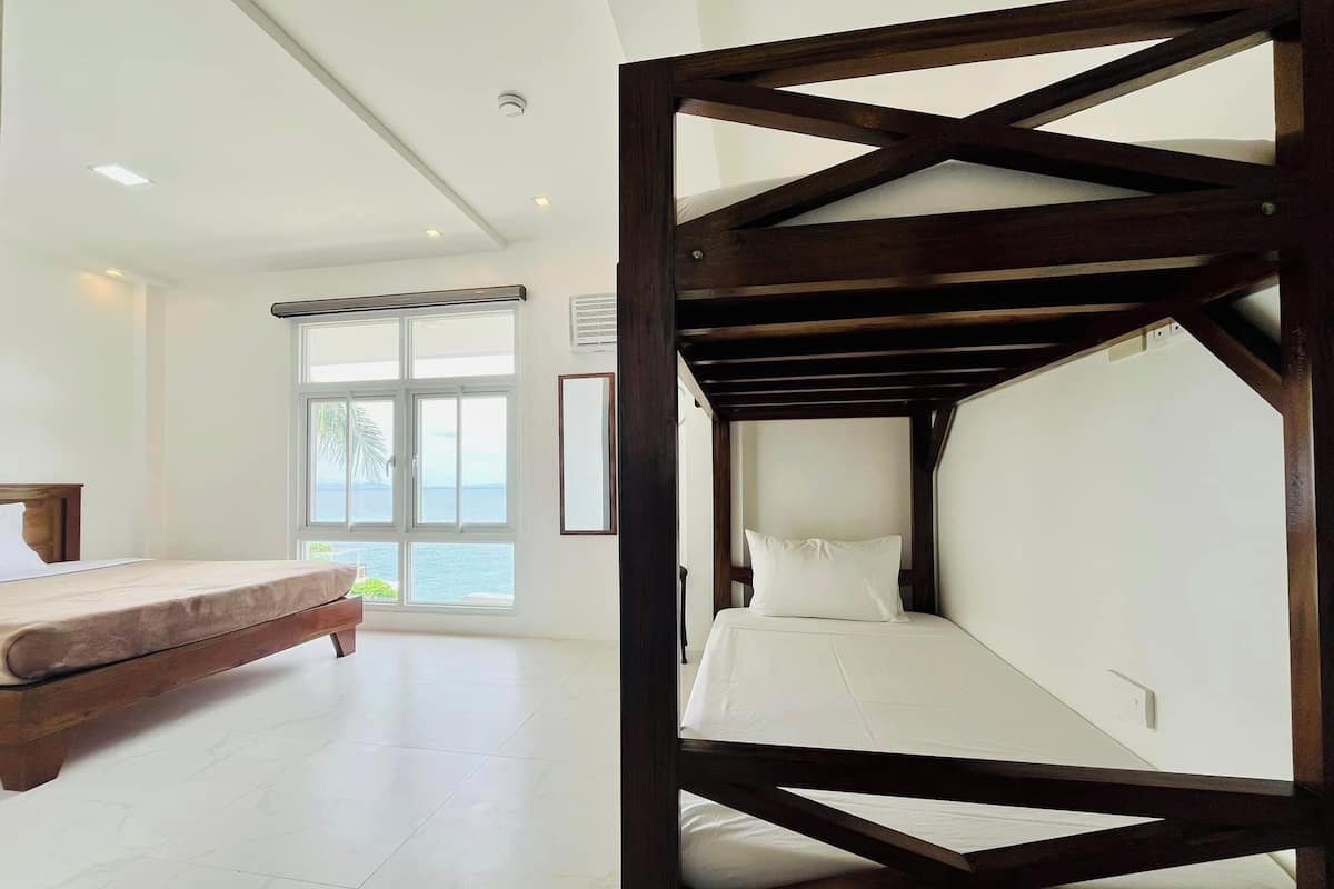 A room with a bed, a bench, and a view of the sea.