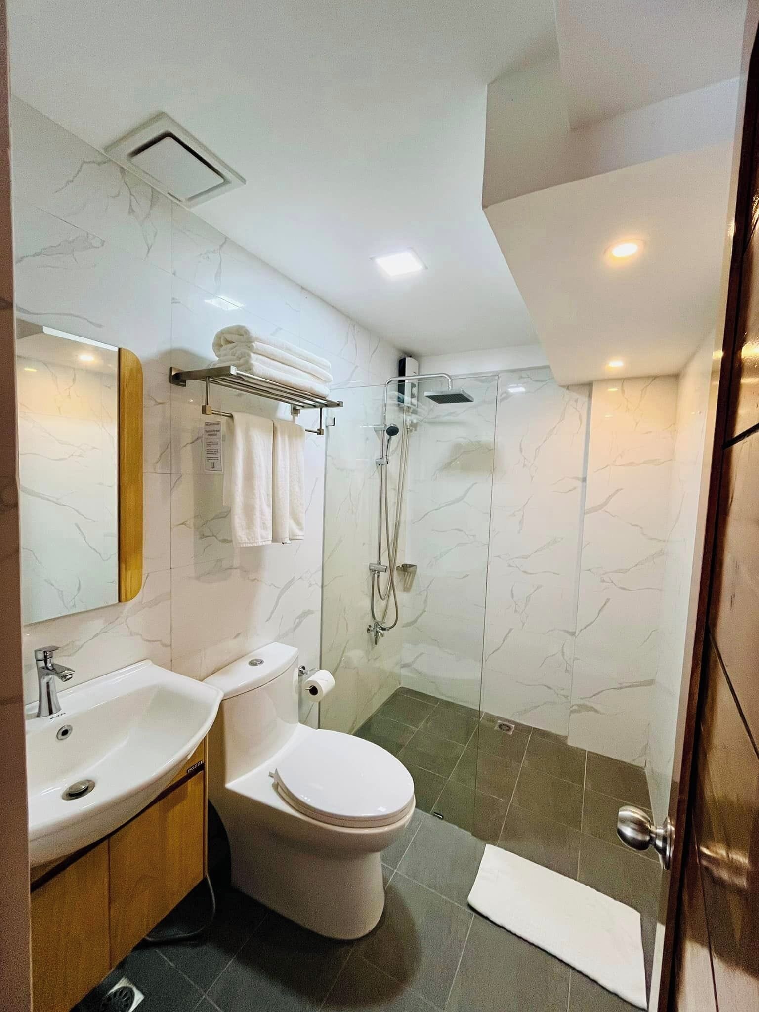 A modern bathroom with a sink, toilet, and glass-enclosed shower.