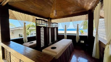 Enjoy a beachside view from the large window in this serene room, featuring a wooden bench and small table.