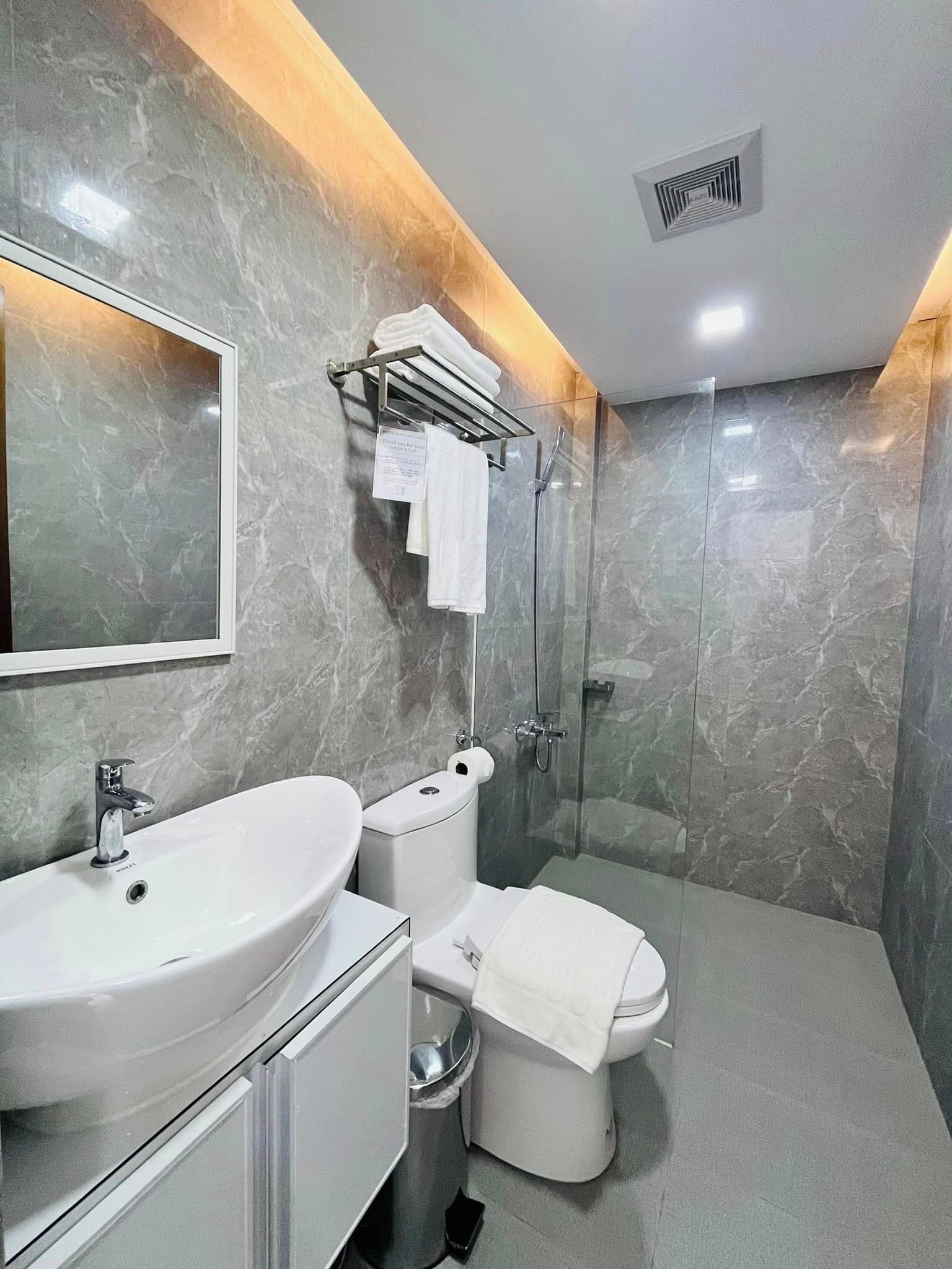 Un baño moderno con un espejo grande, dos lavabos, un inodoro y una ducha.
