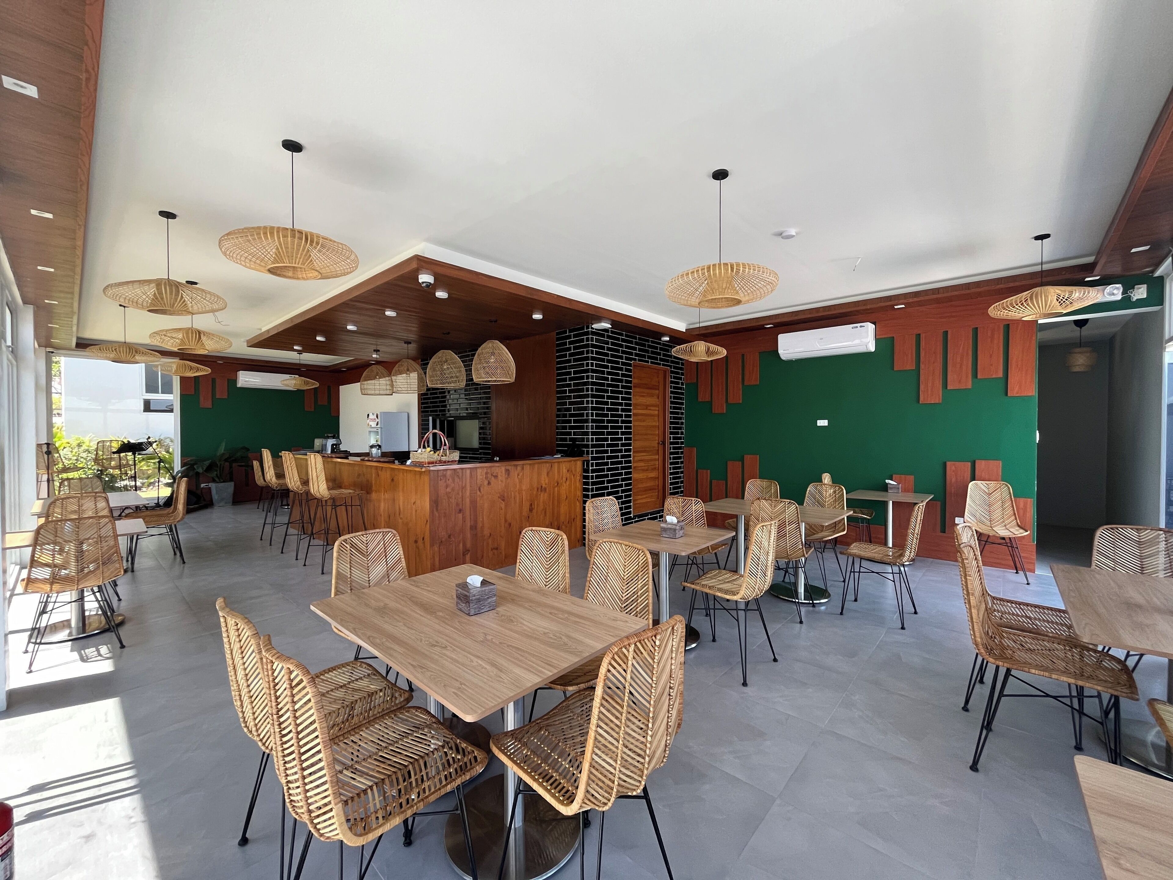 A spacious restaurant with high ceilings, wicker furniture, and a central bar area.