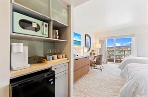 Une chambre d’hôtel équipée d’une kitchenette, d’un lit, d’un bureau et offrant une vue sur la ville.