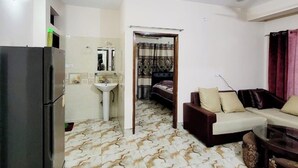 Ein modernes Wohnzimmer mit Sofa, Couchtisch und Küchenzeile, inklusive Kühlschrank und Spüle.