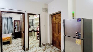 Ein Zimmer mit einem Boden aus Marmoroptik, einer Holztür und einem Kühlschrank mit einer grünen Flasche darauf.