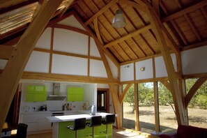 A kitchen with a central island, bar stools, and a view of the outdoors through large windows.