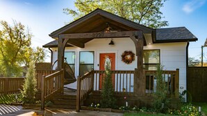 A two-story house with a wooden porch, a red door, and a front yard with flowers. - Kendall Whittier TU, Downtown (Tulsa)