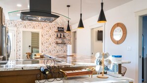 A modern kitchen with a marble countertop, pendant lights, and a wine rack. - Kendall Whittier TU, Downtown (Tulsa)