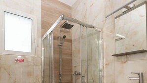 Ein Badezimmer mit Duschkabine, Toilette und Waschbecken mit Spiegel darüber.