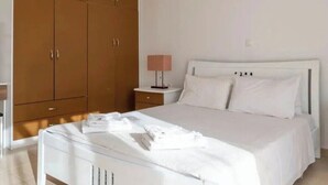 Ein Schlafzimmer mit einem weißen Bett, einem Nachttisch mit Lampe und einem großen Kleiderschrank.