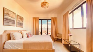 Un dormitorio amplio con una cama grande, un escritorio y vistas a la ciudad.