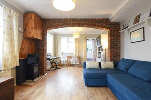 A cozy living room with a blue sofa, a fireplace, and a dining area with a table and chairs.
