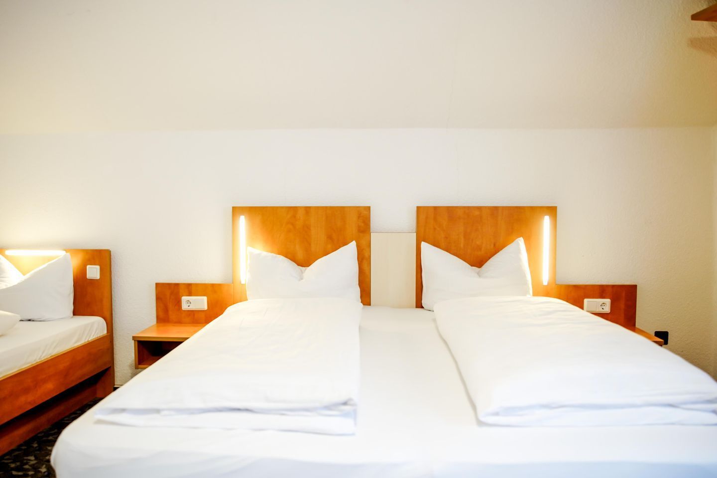Et hotelværelse med to senge, træsengegærder, sengeborde og lamper.