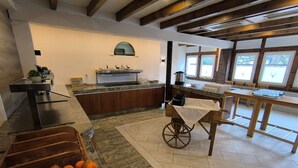Una cuina moderna amb una illa central, una zona de menjador amb taula de fusta, i un cistell de fruita a terra.