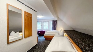 A hotel room with a bed, a mirror, a wooden door, and a window. - Comfortable and versatile room -perfect for relaxation, work and exchange (Winterberg)