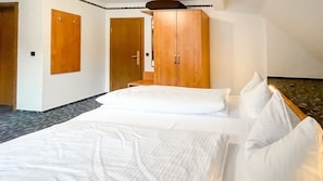 A hotel room with a bed, a wooden wardrobe, a door, and a small table.