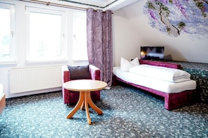 A hotel room with a bed, a TV, a small round table, and a chair.