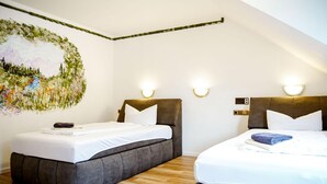A hotel room with two beds, a wooden floor, and a wall mural. - Comfortable and versatile room -perfect for relaxation, work and exchange (Winterberg)